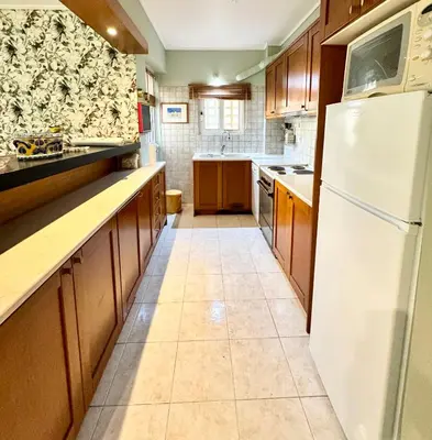 a kitchen with a white refrigerator and wooden cabinets at Varkiza Stay in Varkiza