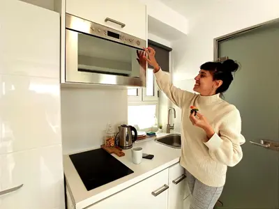 a woman standing in a kitchen fixing a microwave at Rooftop studio with Acropolis view just next to Panathenaic Stadium - 280 Athens view in Athens