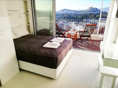 a bedroom with a bed and a balcony with a view at Rooftop studio with Acropolis view just next to Panathenaic Stadium - 280 Athens view in Athens