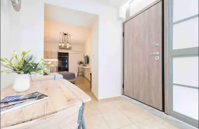 a living room with a wooden table and a large door at Studio In The Heart Of Kallithea in Athens