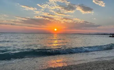 a sunset on the beach with the sun setting at Seaside Charming Apartment in Alimos in Athens
