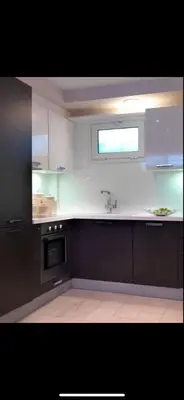 a kitchen with white cabinets and a sink and a window at Small Villa in Palaio Psichiko in Athens