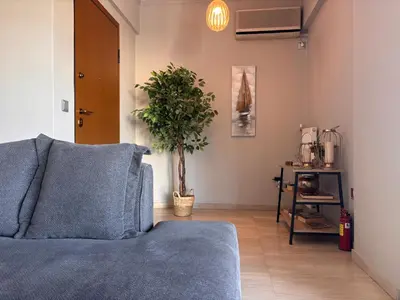 a living room with a blue couch and a plant at Charming Flat in Glyfada Center in Athens