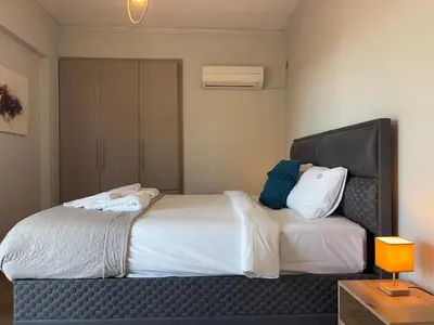 a bedroom with a large white bed with a black headboard at Charming Flat in Glyfada Center in Athens