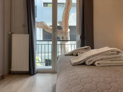 a bedroom with a bed and a large window at Charming Flat in Glyfada Center in Athens