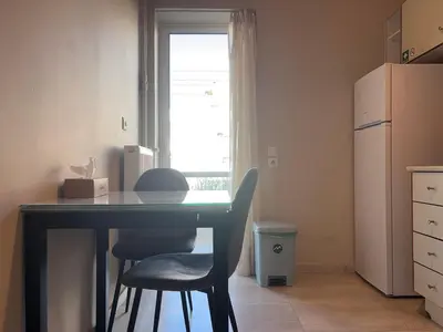 a kitchen with a desk and two chairs and a refrigerator at Charming Flat in Glyfada Center in Athens