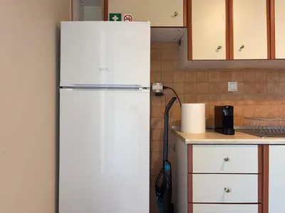 a white refrigerator in a kitchen next to a counter at Charming Flat in Glyfada Center in Athens