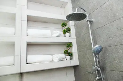 a bathroom with white shelves with towels and plants at Elegant Rooms Athens in Athens