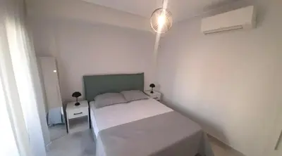 a small white bedroom with a bed and a lamp at Cityacropol in Athens