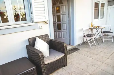 a wicker chair sitting on a porch with a table at Athena's Garden House in Porto Rafti