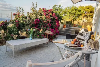 a patio with a table and chairs and flowers at Athena's Garden House in Porto Rafti