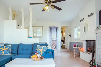a living room with a blue couch and a ceiling fan at Athena's Garden House in Porto Rafti