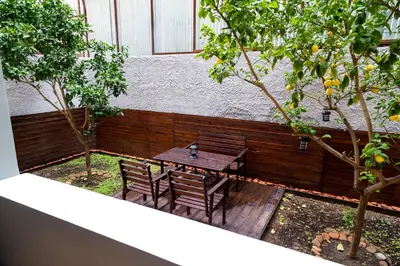 a wooden table and chairs in a courtyard with trees at The Grey House in Piraeus