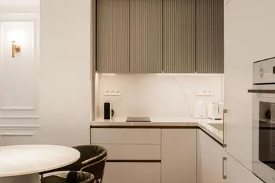 a kitchen with white cabinets and a table at Elegant apartment a breath away from the Acropolis in Athens