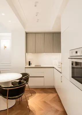 a kitchen with white cabinets and a table and chairs at Elegant apartment a breath away from the Acropolis in Athens