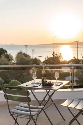 a table with two chairs and a bottle and two glasses at Villa Poseidon Athens Riviera in Lagonissi