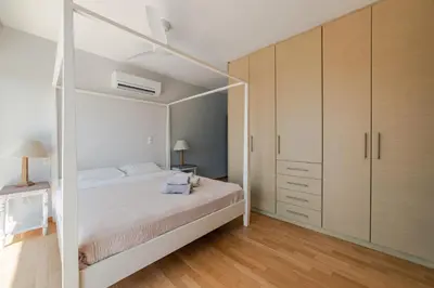 a bedroom with a large white bed and wooden cabinets at Villa Poseidon Athens Riviera in Lagonissi
