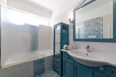 a bathroom with a sink and a mirror and a tub at Villa Poseidon Athens Riviera in Lagonissi