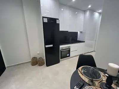 a white kitchen with a table and a black refrigerator at BlueMotion - Ferry 65 #2 in Piraeus