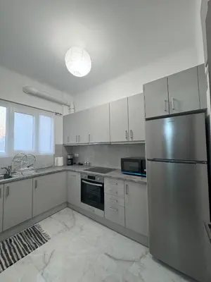 a kitchen with white cabinets and a stainless steel refrigerator at Ntinos Apartment Center Exarcheia in Athens