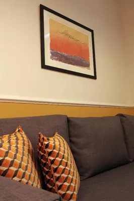 a couch with two pillows sitting under a picture at Absolute Athens Acropolis Muses in Athens