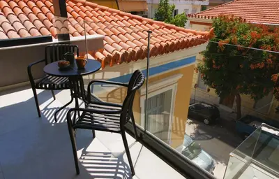 a table and chair on a balcony with a building at Absolute Athens Acropolis Muses in Athens