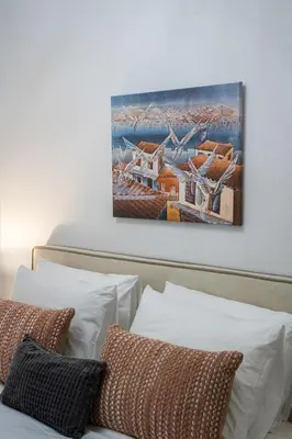 a painting hanging above a bed with white pillows at Villa Costa Luca in Vouliagmeni in Athens