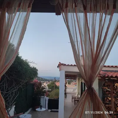 a view of a house with curtains on a balcony at Skyline Serenity in Lagonissi