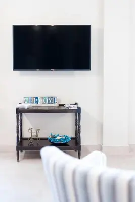 a living room with two white chairs and a tv at Renovated fully equipped 2 Bedroom cozy Apartment near the sea in Athens
