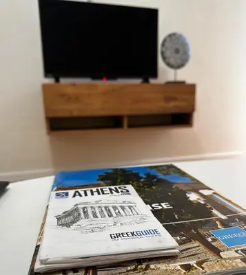 a magazine sitting on a table with a television at Petralona modern apartment near metro & Acropolis in Athens