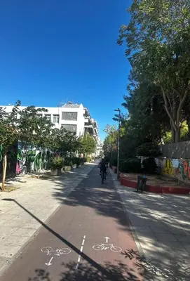 a person riding a bike down a city street at Petralona modern apartment near metro & Acropolis in Athens