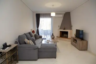 a living room with a gray couch and a tv at Athens Airport Zen House in Paianía