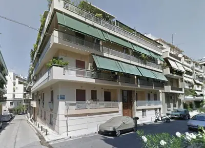 a large white building with a balcony and cars parked on the street at Marmaronetta in Athens