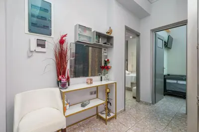 a living room with a white chair and a mirror at Gazi Suite with Private Rooftop in Athens