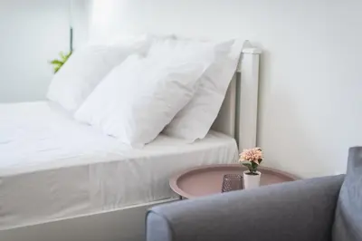 a bed with white pillows and a table and a chair at Kallithea Kyprou Square ! in Athens
