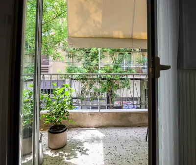 a sliding glass door with a potted plant on a balcony at Koukaki Beat in Athens
