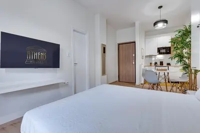 a white bedroom with a white bed and a kitchen at Historical center Athens amazing studio in Athens