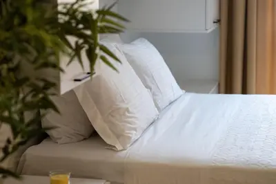 a white bed with white pillows and a plant at Historical center Athens amazing studio in Athens