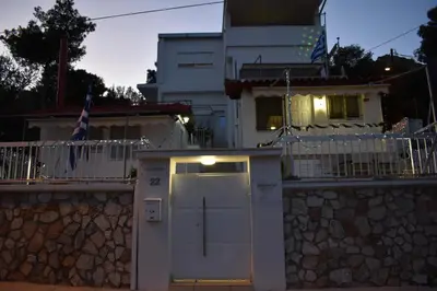 a white house with a stone wall and a door at Panorama Γλυκά Νερά - Athens in Glyka Nera