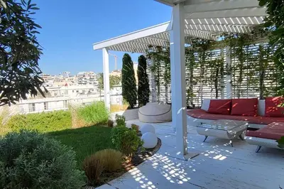 a patio with a red couch under a pergola at Spacious top flat with panoramic rooftop in Athens