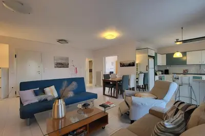 a living room with a blue couch and a kitchen at Spacious top flat with panoramic rooftop in Athens