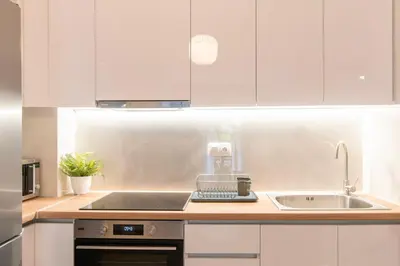 a kitchen with white cabinets and a sink at Ella's Cozy escape with balcony! in Athens