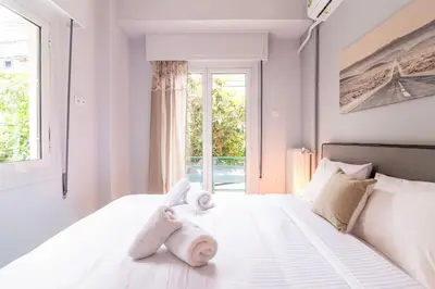 a white bedroom with towels on a bed with a window at Ella's Cozy escape with balcony! in Athens