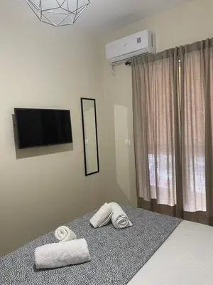 a bedroom with two towels on a bed with a television at Byrons Cozy Place in Athens