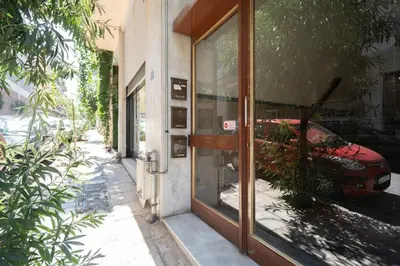 a glass door of a building with a red car outside at LIV - Peaceful Pagrati Getaway in Athens