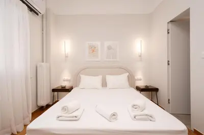 a bedroom with a white bed with towels on it at LIV - Peaceful Pagrati Getaway in Athens