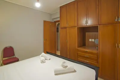 a bedroom with a bed with wooden cabinets and a red chair at Seaside Spacious 2 BR, 2BA, Sea view Apt in Piraeus