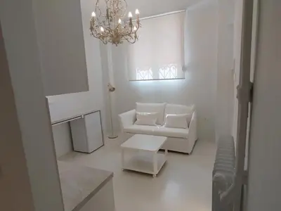 a white living room with a white couch and a chandelier at AMG Stylish Small Apartment in Pagkrati Close to Metro in Athens