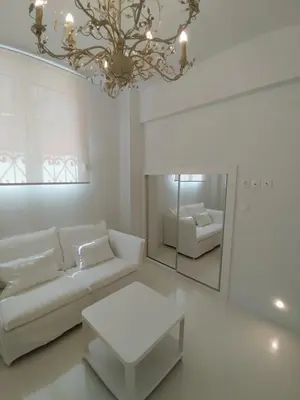 a white living room with a couch and a mirror at AMG Stylish Small Apartment in Pagkrati Close to Metro in Athens