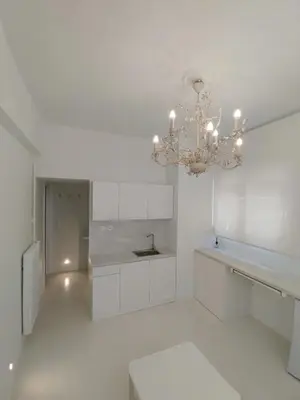a white kitchen with a chandelier in a room at AMG Stylish Small Apartment in Pagkrati Close to Metro in Athens